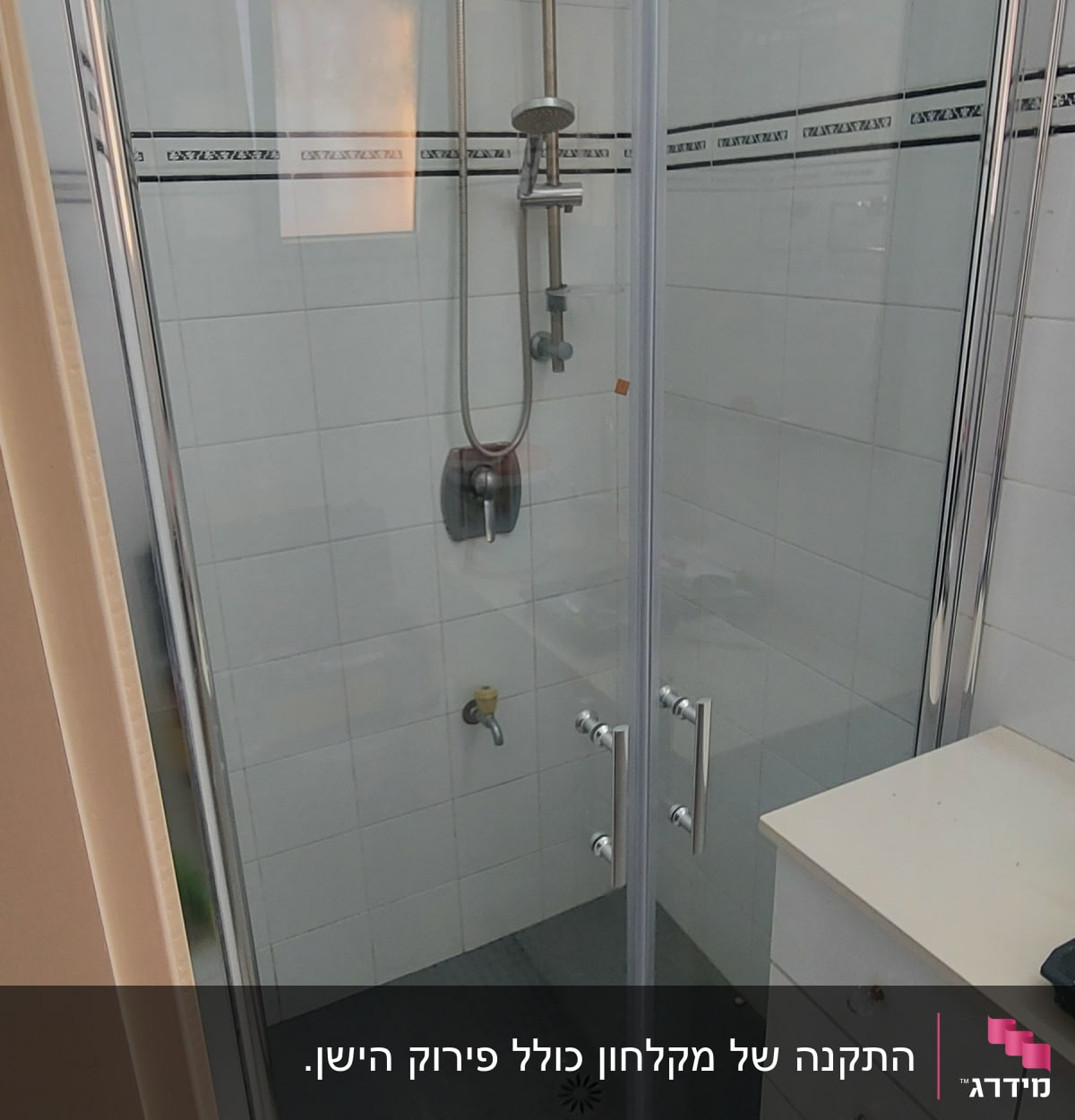 מקלחון זכוכית עם ראש מקלחת מתכתי וקירות אריחים לבנים